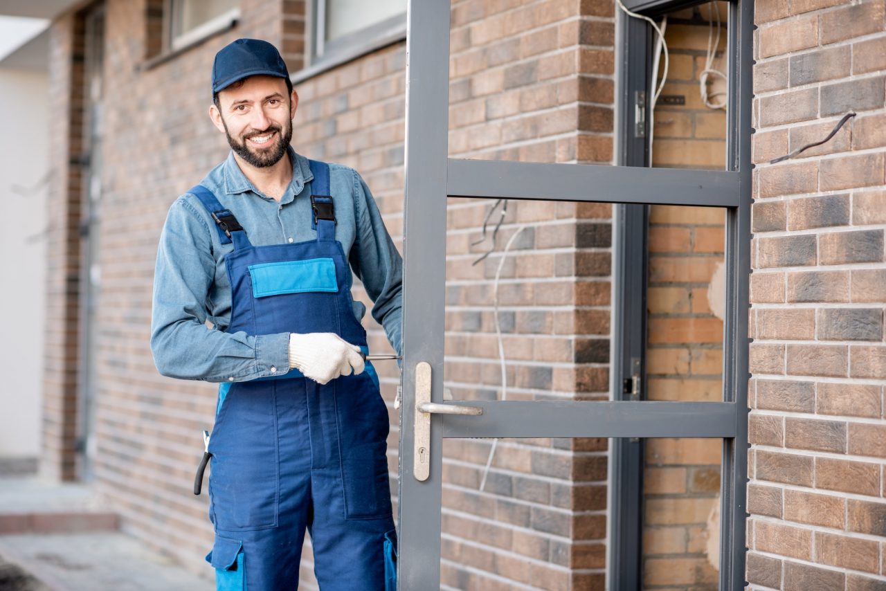 Smiling locksmith standing at a front door